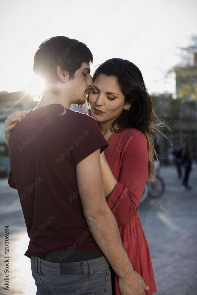Affectionate young couple standing on city square at sunset Affectionate young couple standing on city square at sunset