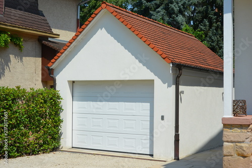 Beton-Garage mit Automatik-Tor, Satteldach, Dachrinne, Wasserfangkasten und Regenfallrohr in der Hauszufahrt