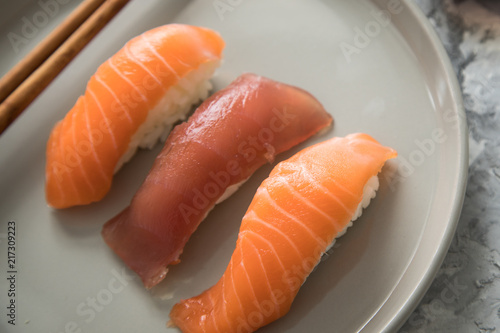 Lachs und Tunfisch Nigiri Sushi mit Holz Stäbchen auf Porzellan Teller