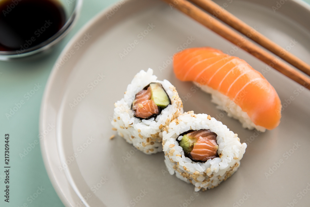 Lachs Nigiri und Inside Out California Sushi mit Avocado, Sojasauce und Holz Stäbchen auf Porzellan Teller Lachs Nigiri und Inside Out California Sushi mit Avocado, Sojasauce und Holz Stäbchen auf Porzellan Teller