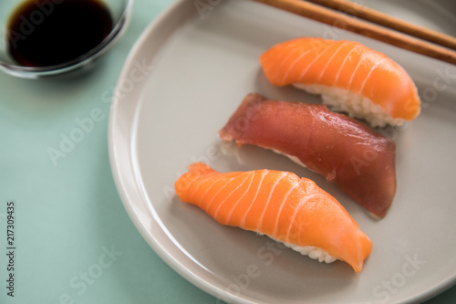 Lachs und Tunfisch Nigiri Sushi mit Sojasauce und Holz Stäbchen auf Porzellan Teller