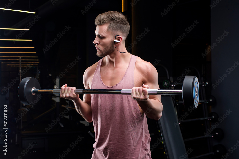 Guy bodybuilder in the gym shakes muscles. Top view, copy space Guy bodybuilder in the gym shakes muscles. Top view, copy space