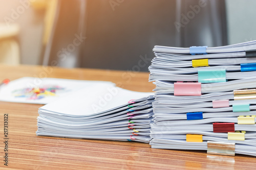 Stack of student's homework that assigned to students to be completed outside class on teacher's desk separated by colored paper clips. Document stacks arranged by various colored paper clips on desk. © NuPenDekDee