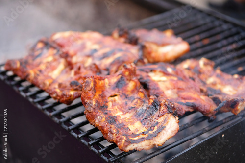 Beef ribs on grill grate in open air. Roasted meat on the fire. Traditional meat cooking.