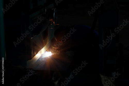 The welder at the industrial plant makes the connection using an electric arc.