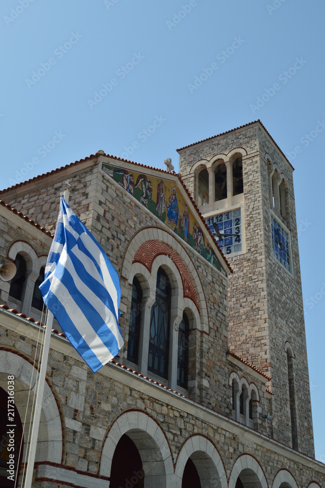 Orthodox Church Of Konstantinos With The Beautiful Blue And White Greek Flag Waving In The Wind. Architecture History Travel.4 July 2018. Volos. Magnesia. Greece.