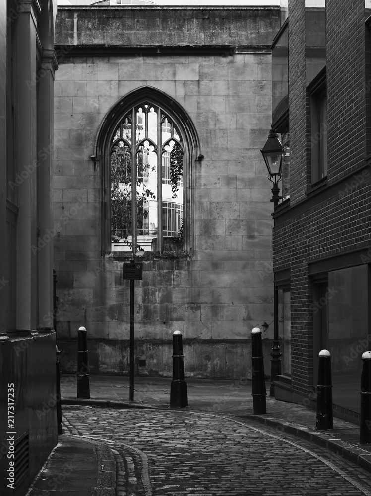 Black and white image of an atmospheric alley with cobblestone..