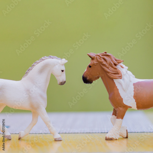 two plastic toy horses on wooden table  copy space for text