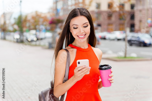 Young Asian girl with a paper cup of coffee taking away and smar photo