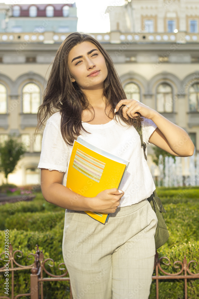 A female student with books on the background of the university. A female student with books on the background of the university.