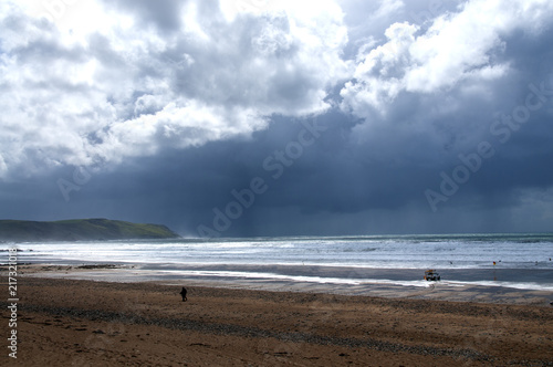 фотографія walker on the beach with storm coming