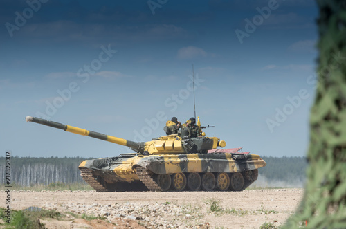 Military or army tank ready to attack and moving over a deserted battle field terrain. a lot of dust.