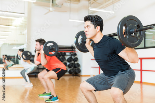 Man Exercising With Barbell In Health Club