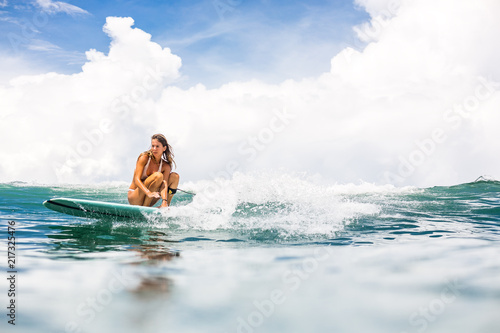 Canvas Print Beautiful young surfer lady in sexy pink bikini surfing longboard on the big waves in the open ocean