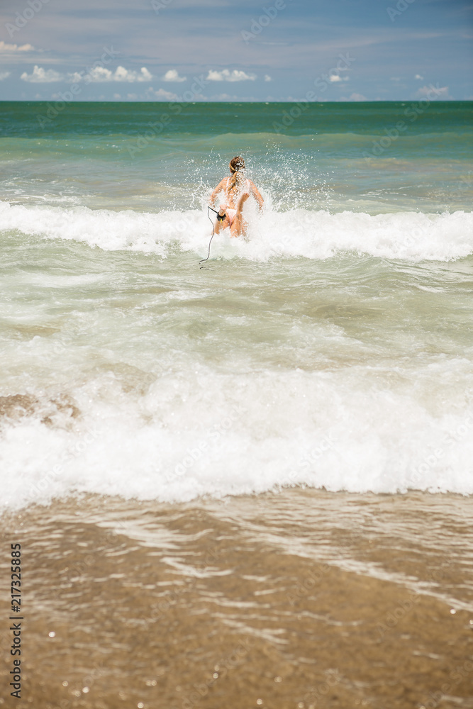 Beautiful young slim lady in sexy pink bikini with long custom surfing board single fin in waves of blue ocean ready to surfing. Tropic island vacation. Summer travel girl, active hipster lifestyle. Beautiful young slim lady in sexy pink bikini with long custom surfing board single fin in waves of blue ocean ready to surfing. Tropic island vacation. Summer travel girl, active hipster lifestyle.