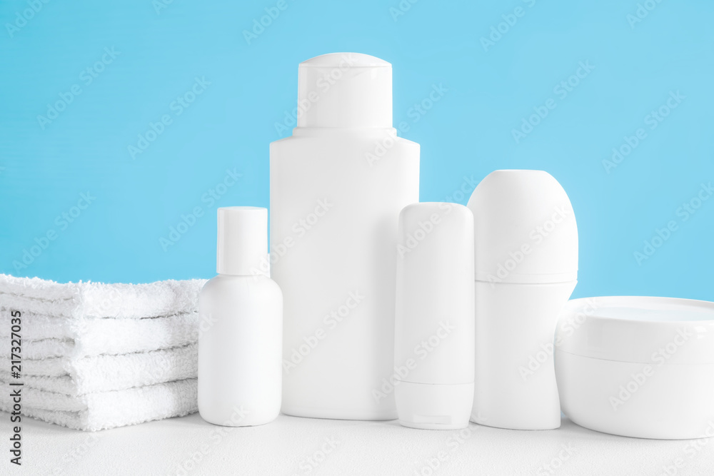 Different, white beauty toiletries, cream jar and towels on the blue background. Body relax and care products for women and men. Front view. Different, white beauty toiletries, cream jar and towels on the blue background. Body relax and care products for women and men. Front view.