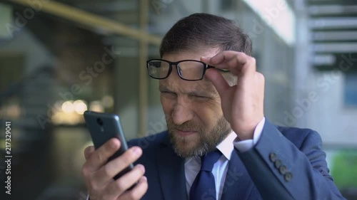 Manager in eyeglasses trying read smartphone message, poor eyesight, health care