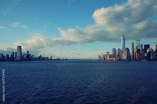New York City skyline with urban skyscrapers over Hudson River. Manhattan downtown panorama. Waterfront view to the harbor at sunset.