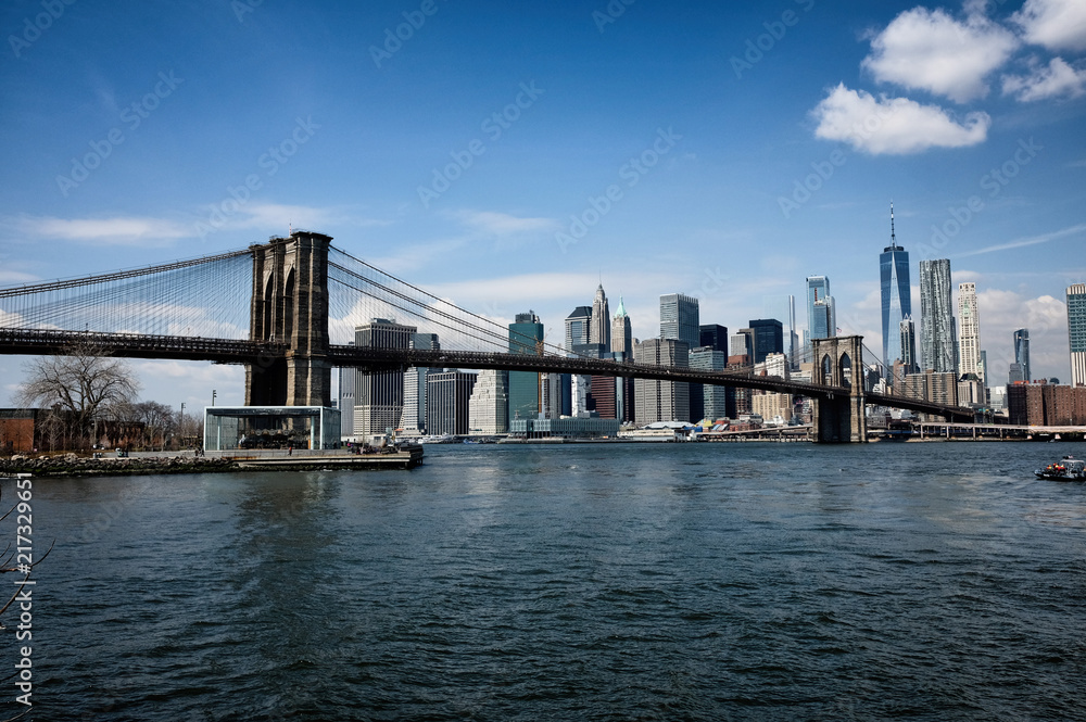 Brooklyn bridge with New York City skyline panoramic spring view. Lower Manhattan downtown scenery from Brooklyn Bridge Park riverbank in Dumbo district, NYC, USA.