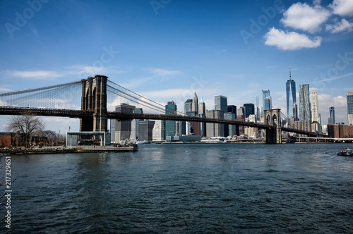 Brooklyn bridge with New York City skyline panoramic spring view. Lower Manhattan downtown scenery from Brooklyn Bridge Park riverbank in Dumbo district, NYC, USA.