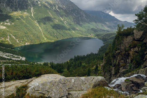 Aerial view shot of beautiful green hills and mountains in dark clouds and reflection on the lake Morskie Oko lake, High Tatras, Zakopane, Poland.