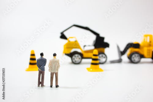 Miniature businessman with construction car.