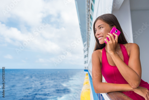Cruise ship woman using mobile cellphone calling on travel vacation. Asian girl on travel holidays. Internet international call concept. Tourist talking on smartphone at sea.