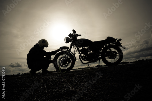 Motorcycle or motorbike Silhouette with male rider standing at the river.