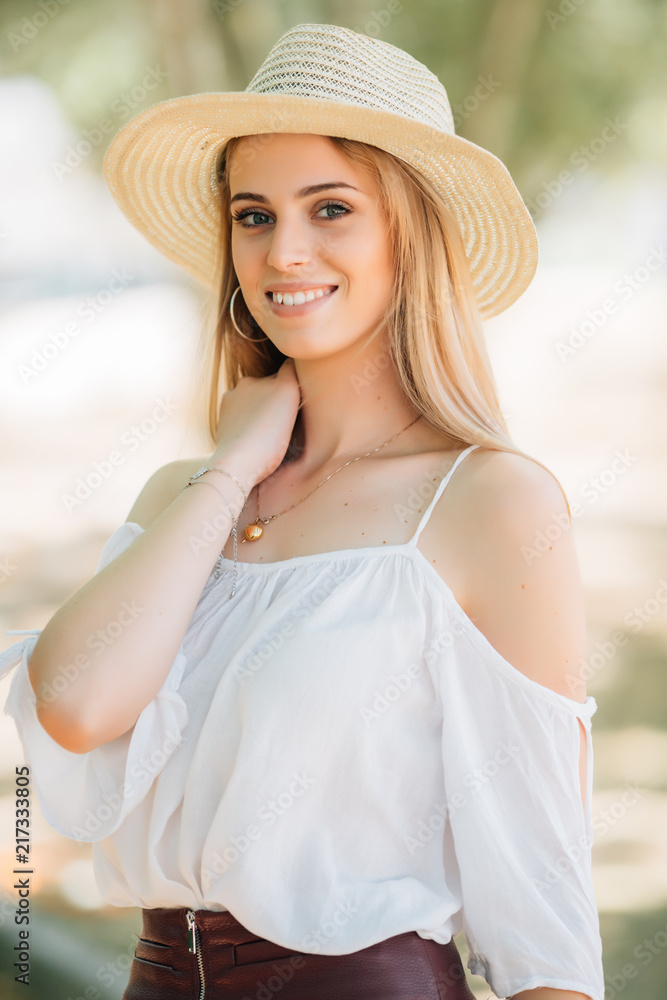 Young smile beautiful woman with straw hat walking the summer streets