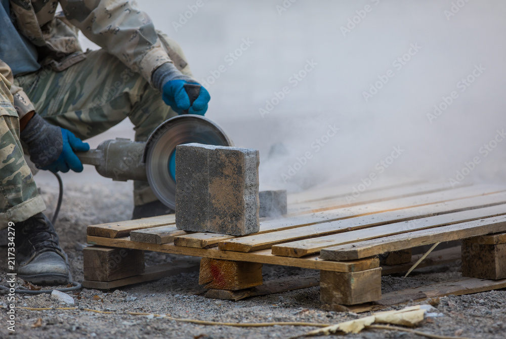 worker cuts stone tiles with electric saws