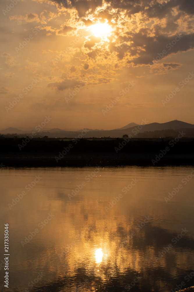 sunrise in front of water with clouds