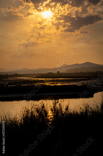 sunrise in front of water with clouds