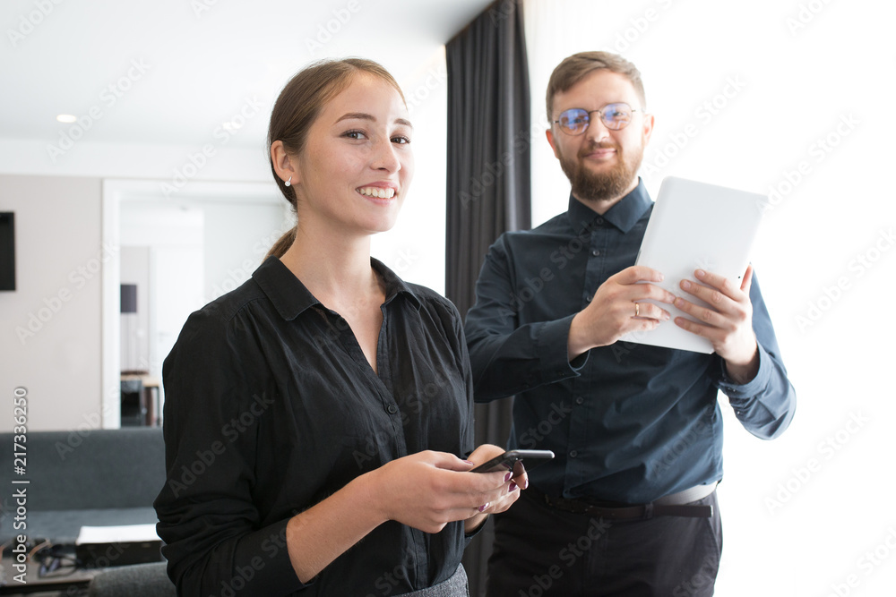 bearded white man in a black shirt, round glasses and a white medical tablet in hands in the doorway with a white girl in a black shirt and phone in hand bearded white man in a black shirt, round glasses and a white medical tablet in hands in the doorway with a white girl in a black shirt and phone in hand