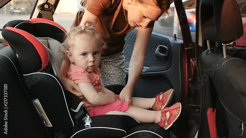 mom puts the child in the car seat