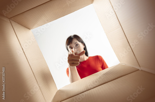 The surprised woman unpacking, opening carton box and looking inside. The package, delivery, surprise, gift, lifestyle concept. Human emotions and facial expressions concepts © master1305