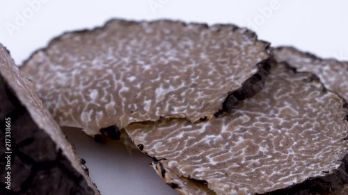 Super macro of black truffle slices slowly rotating on the on the turntable. Isolated on the white background. Closeup.