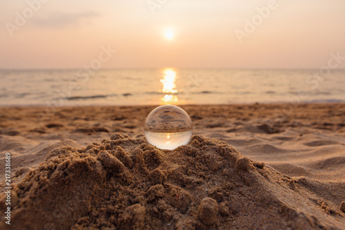 Lens ball on the sand with reflection of sea and sunset on the beach