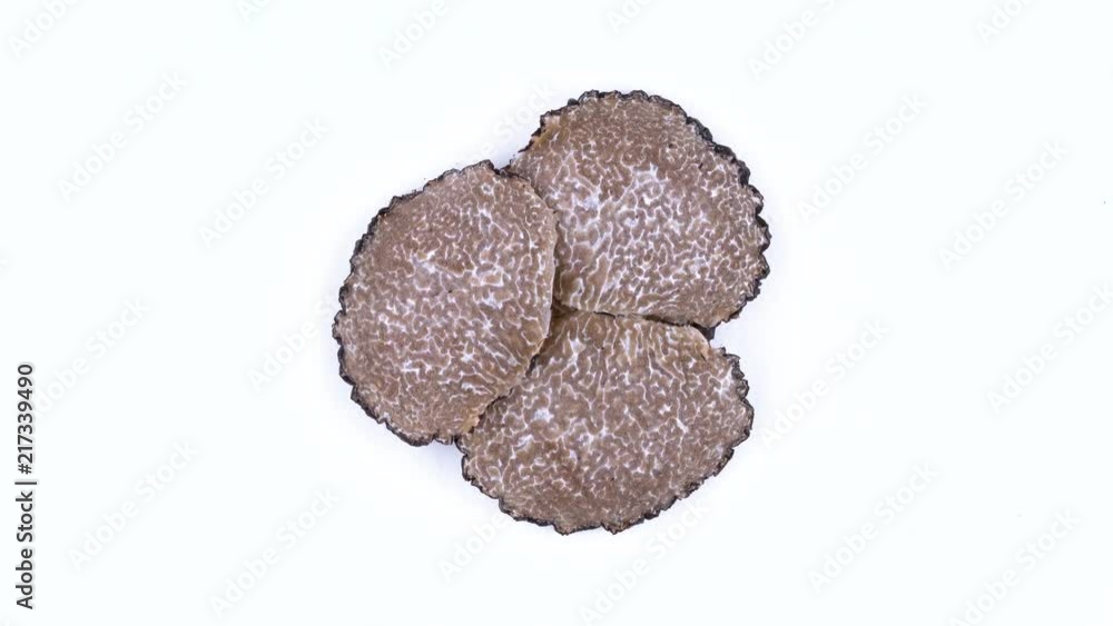 Top view from above of black truffle slices slowly rotating on the on the turntable. Isolated on the white background. Closeup. Macro. Top view from above of black truffle slices slowly rotating on the on the turntable. Isolated on the white background. Closeup. Macro.