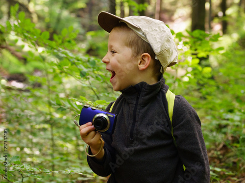 Portrait of children taking photos with a camera in the forest. Scene in the summer, large blur background.