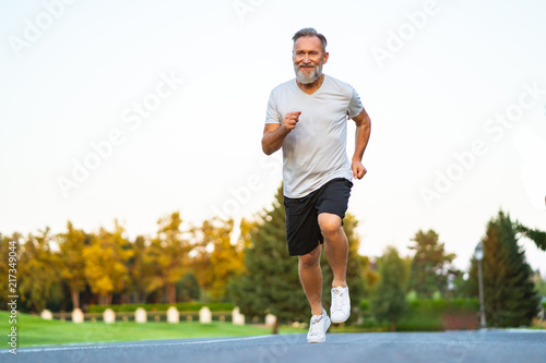 The happy elderly man running on the road