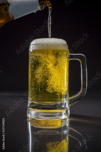 Pouring beer, Pint glass with beer on black background, Glass of cold light beer with foam