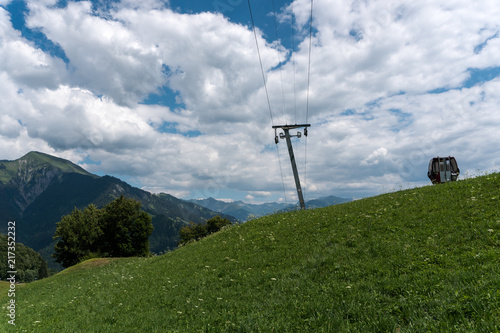 A ski lift in a summertime meadow with an empty cable railway cabin next to it near Seewis in Switzerland photo