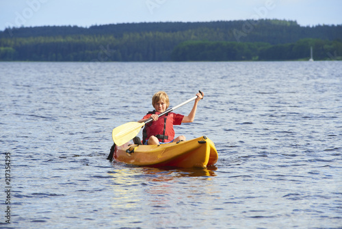Active happy child. Teenage school boy having fun enjoying adventurous experience kayaking on the lake on a sunny day during summer vacation © Petr Bonek