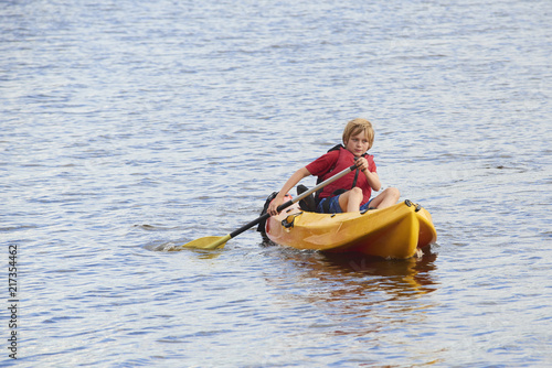 Active happy child. Teenage school boy having fun enjoying adventurous experience kayaking on the lake on a sunny day during summer vacation
