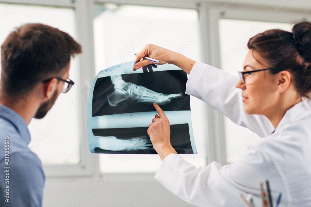 Portrait of Woman Doctor at her Medical Office Looking at X-Ray with Patient Portrait of Woman Doctor at her Medical Office Looking at X-Ray with Patient
