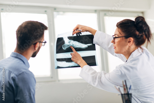 Portrait of Woman Doctor at her Medical Office Looking at X-Ray with Patient