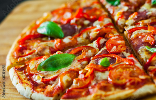 slices of Pizza with Mozzarella cheese, Ham, Tomatoes, salami, pepper, pepperoni Spices and Fresh Basil. Italian pizza