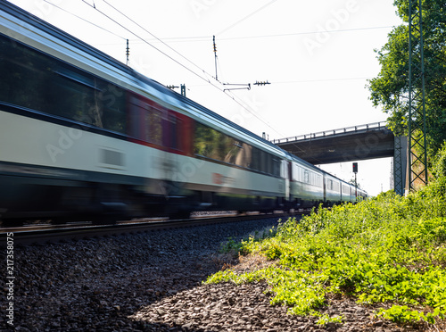 A moving railway train under the viaduct on a summer sunny day in western Germany.