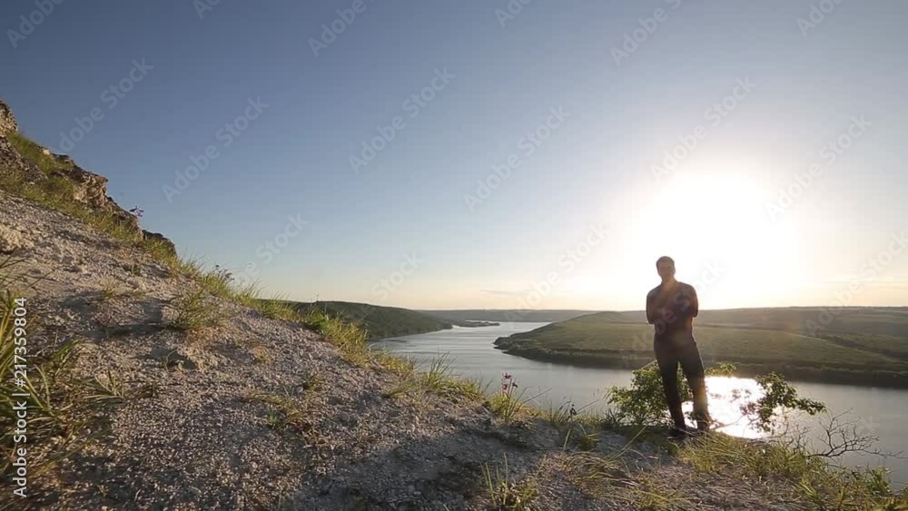Young attractive man standing othe lands edge and looking far away. Superwide shot. Young attractive man standing othe lands edge and looking far away. Superwide shot.