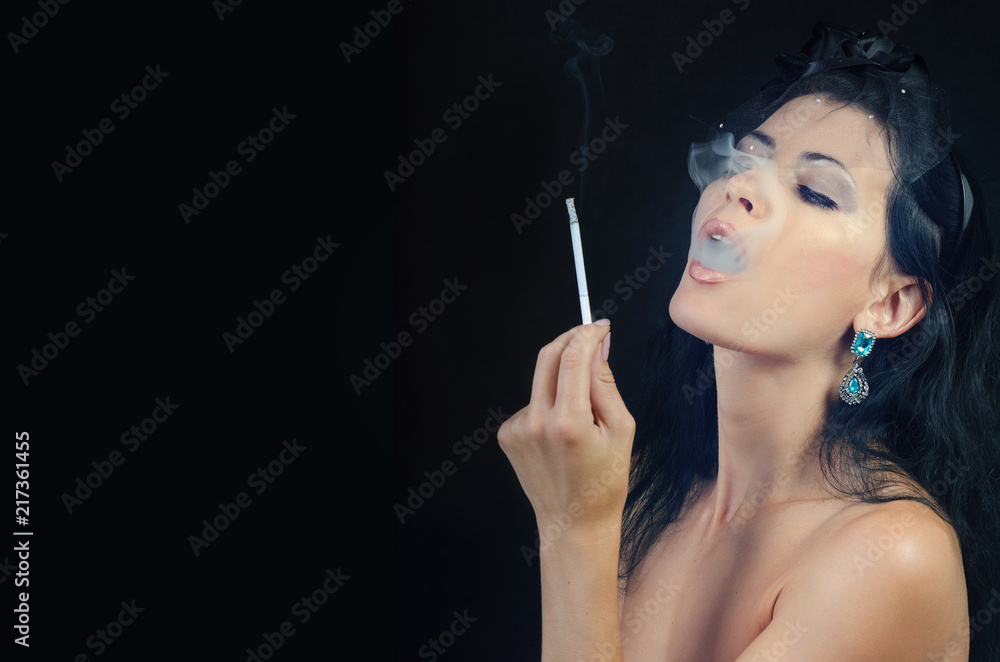 Obraz premium woman releasing smoke holding a cigarette in her hand